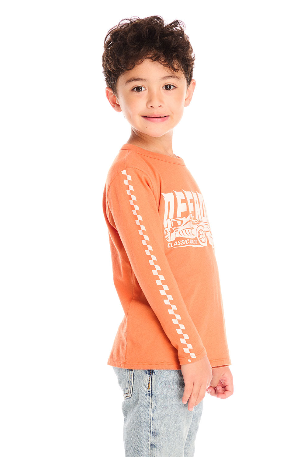 Side view of boy wearing Chaser’s Raceway Speed orange long-sleeve top with racing checker detail in white on the sleeve on a white background