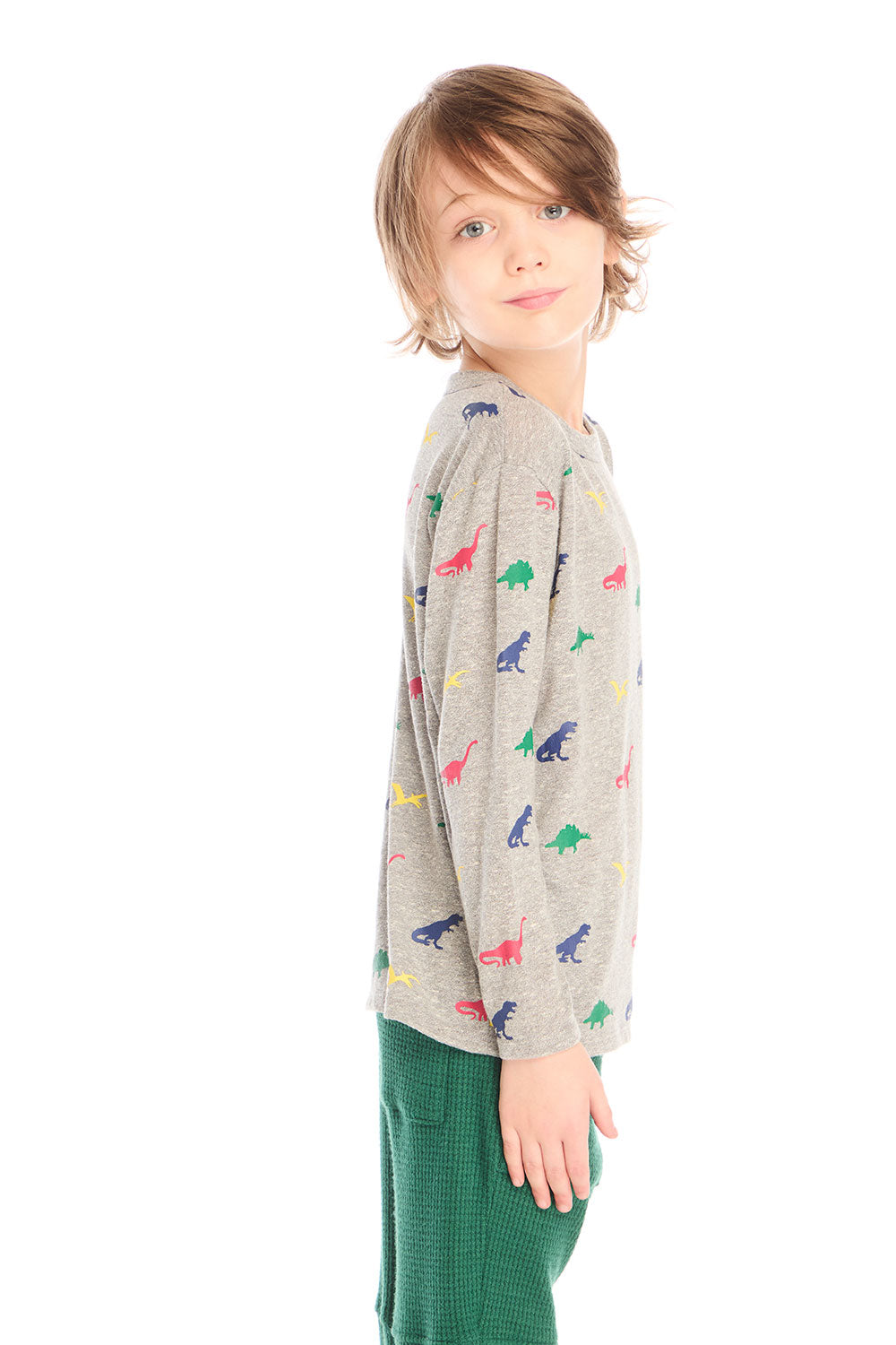  Side view of boy wearing Chaser’s Multi Dinos grey long sleeve top with colorful dinosaur patterns against a white background