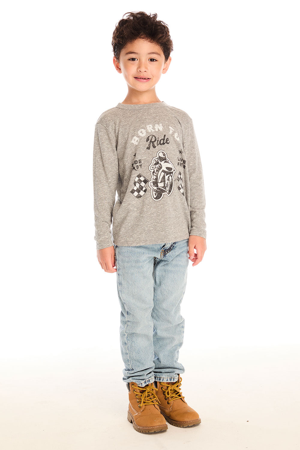 Full body view of boy wearing Chaser’s Off To The Races grey long sleeve top with motorcycle and race flag graphic and “Born to Ride” text, paired with light blue jeans on a white background