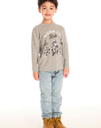 Full body view of boy wearing Chaser’s Off To The Races grey long sleeve top with motorcycle and race flag graphic and “Born to Ride” text, paired with light blue jeans on a white background