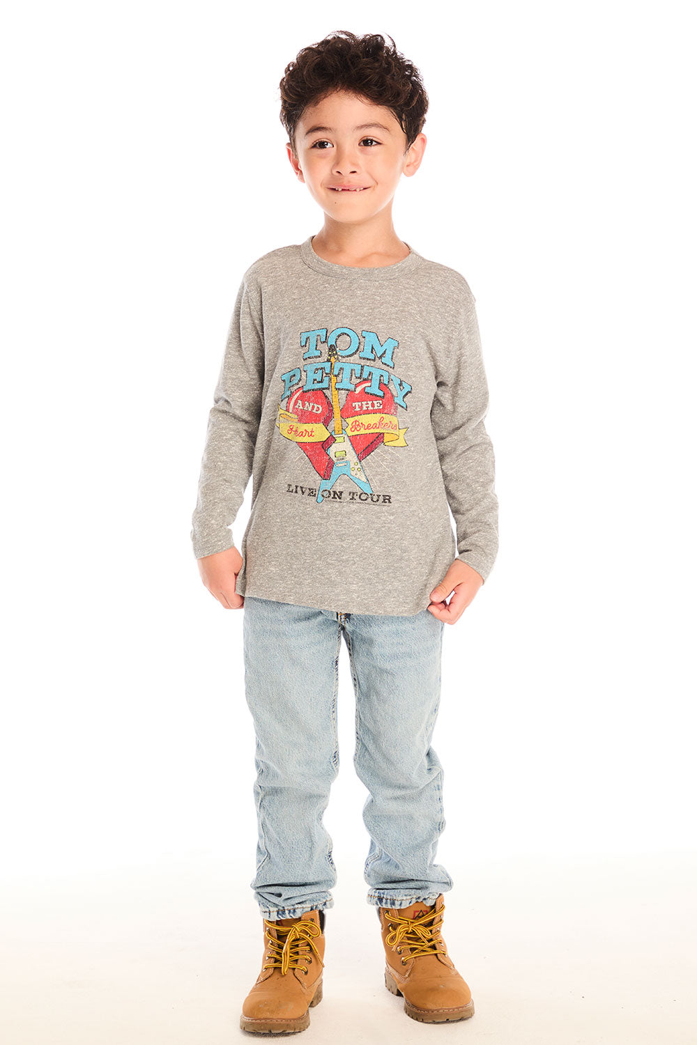 Full body view of boy wearing Chaser’s Tom Petty Live On Tour gray long-sleeve top with a broken heart and guitar graphic design and light blue jeans on a white background