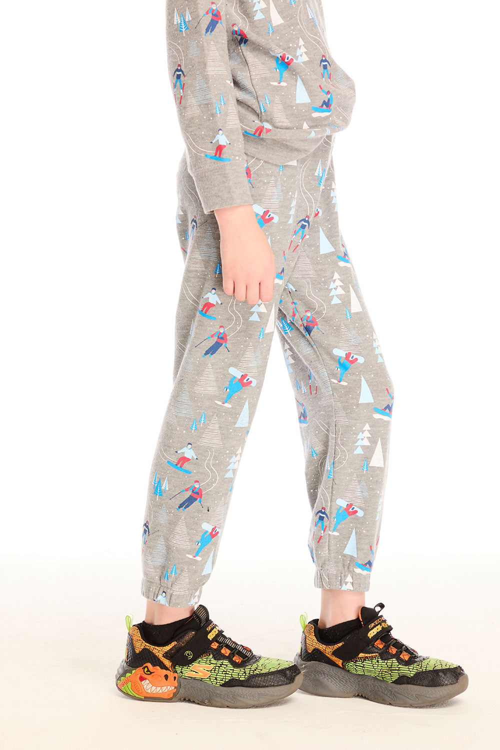 Side view of boy wearing Chaser's gray Allover Ski Slope Pants and matching top with colorful patterns on a white background