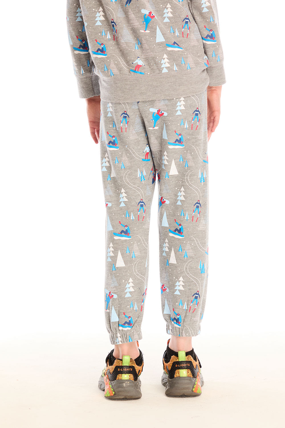 Back view of boy wearing Chaser's gray Allover Ski Slope Pants and matching top with colorful patterns on a white background