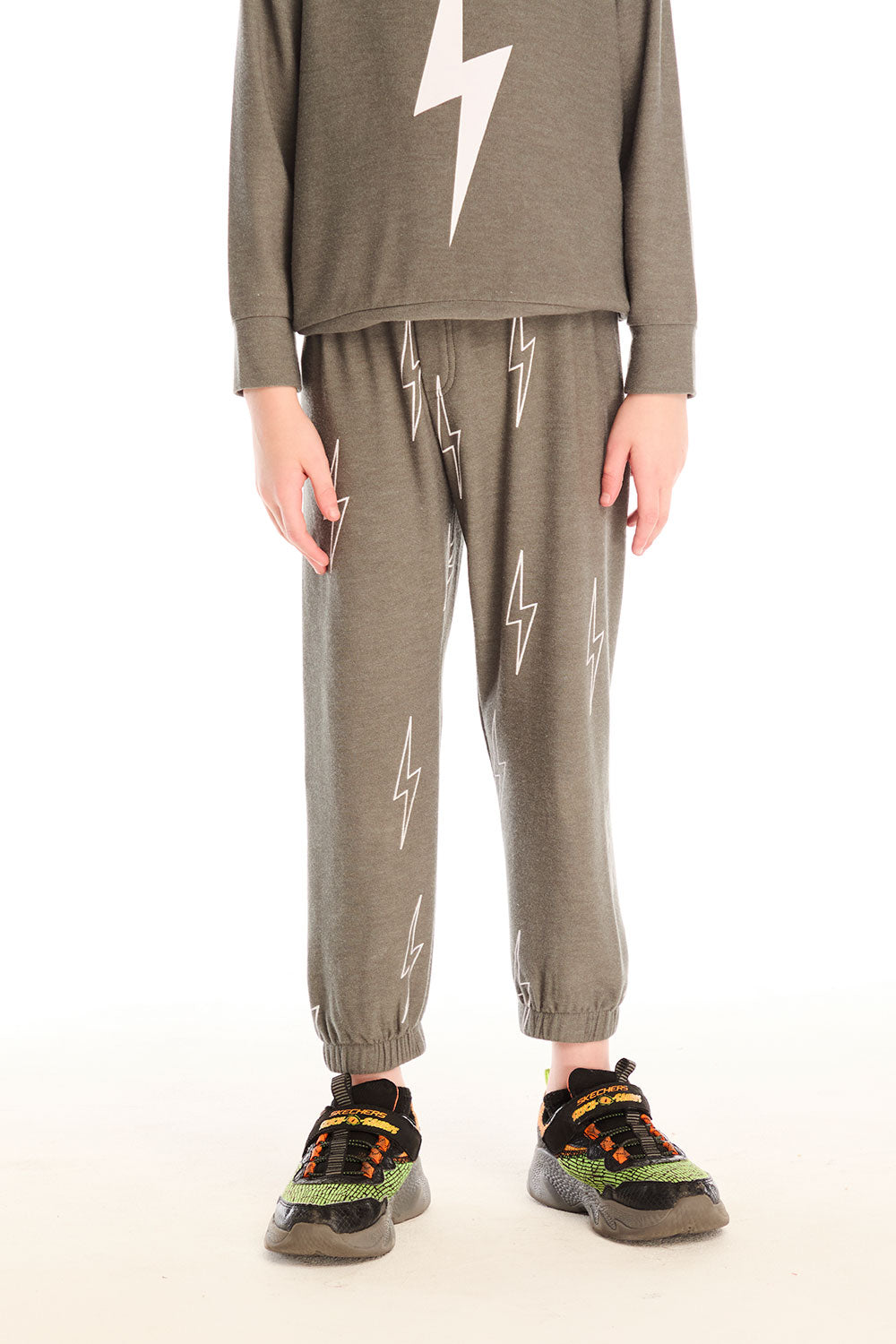 Boy wearing Chaser's green Allover Bolts Pants with lightning bolt designs on a white background