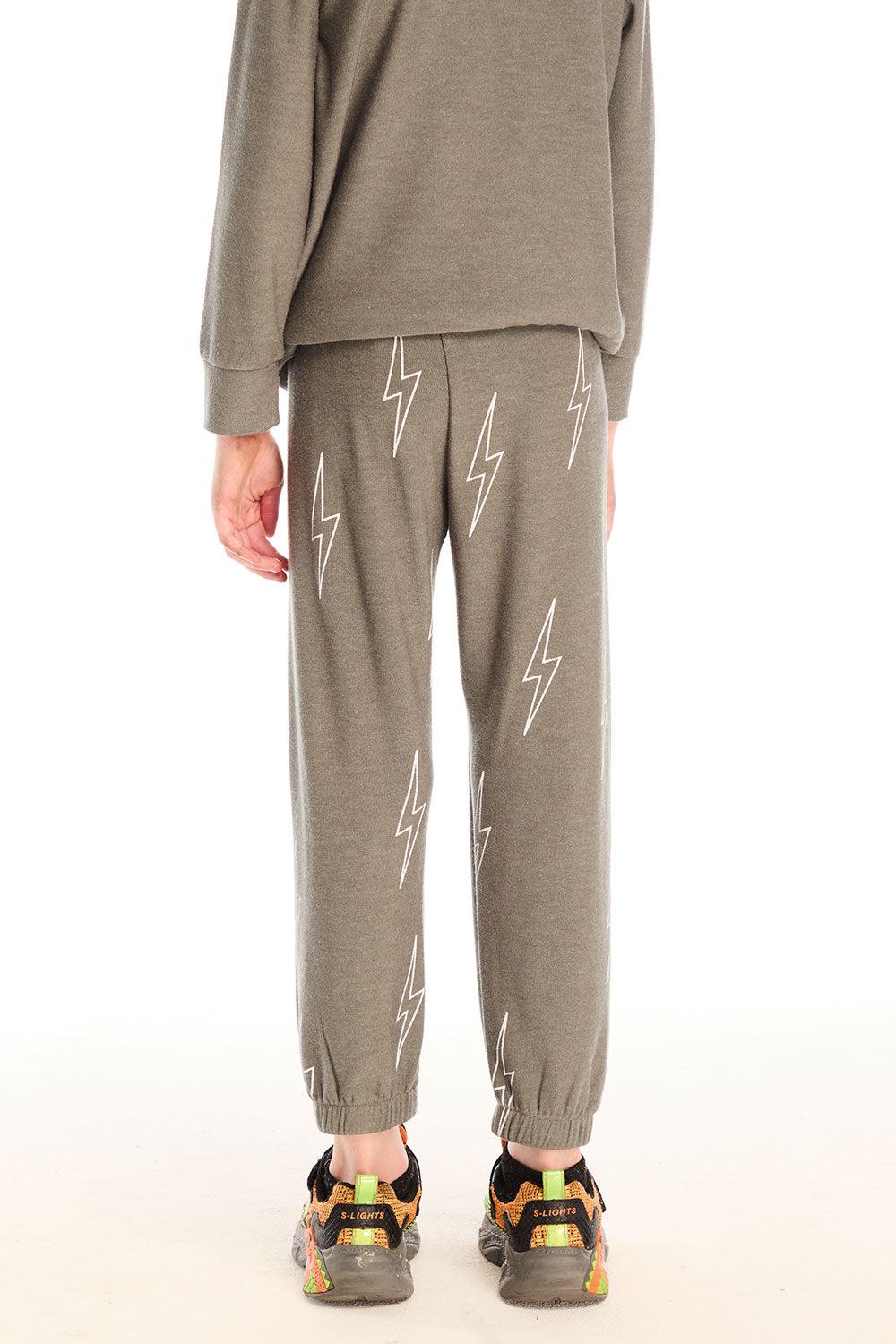 Back view of boy wearing Chaser's green Allover Bolts Pants with lightning bolt designs on a white background