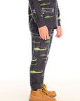 Side view of boy wearing Chaser's dark gray Allover Helicopters pant with green airplane patterns and matching top on a white background