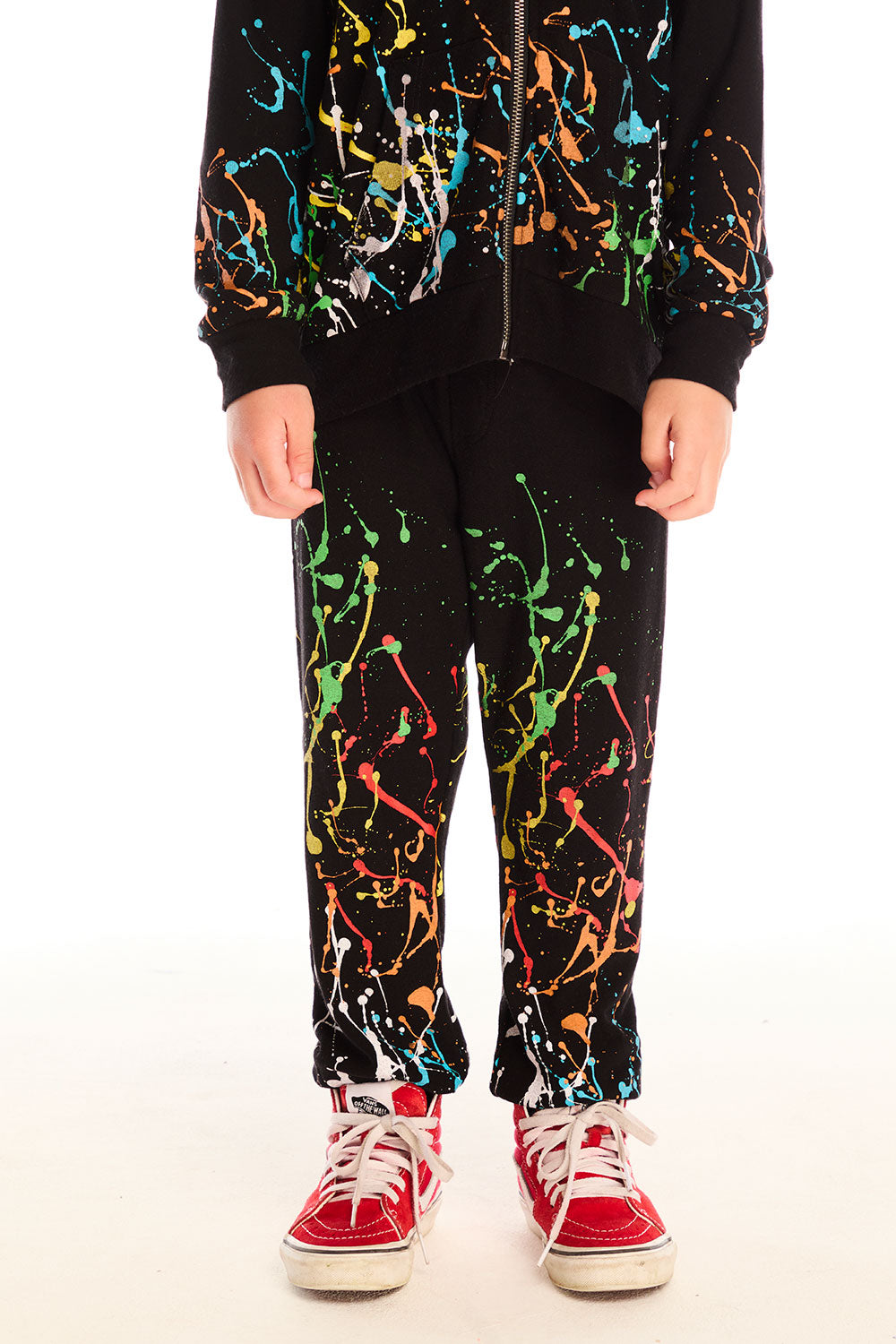 Front view of boy wearing Chaser’s Paint Splatter black pants with colorful splatter design against a white background
