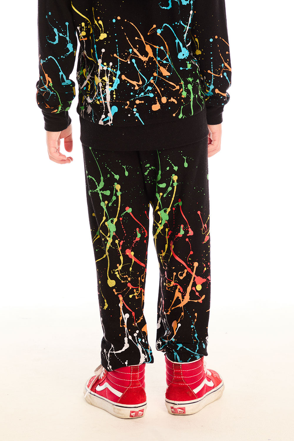 Back view of boy wearing Chaser’s Paint Splatter black pants with colorful splatter design against a white background