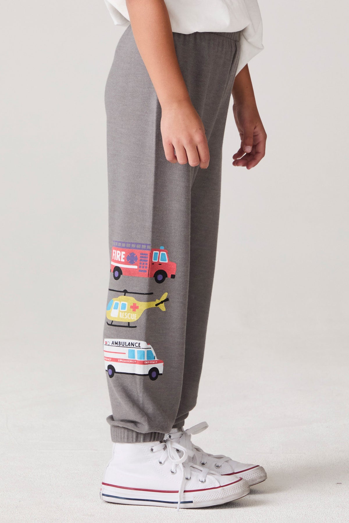 Model wearing Chaser's Heroes Boys Jogger in charcoal with first-responder vehicle graphics, side view