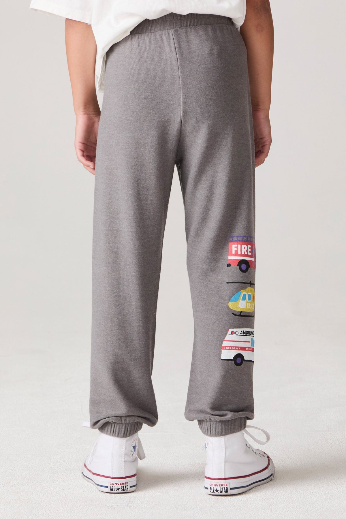 Model wearing Chaser's Heroes Boys Jogger in charcoal with first-responder vehicle graphics, back view