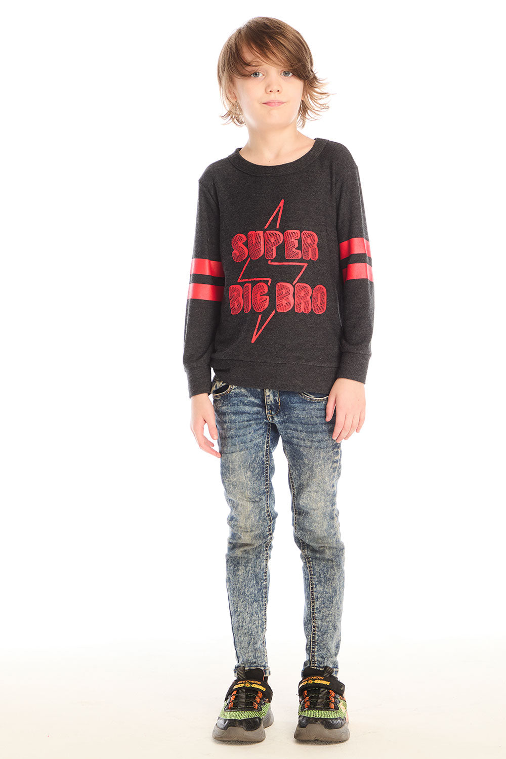 Full body view of boy wearing Chaser’s Best Brother Ever black long-sleeve shirt with red text and striped sleeves, paired with blue jeans on a white background