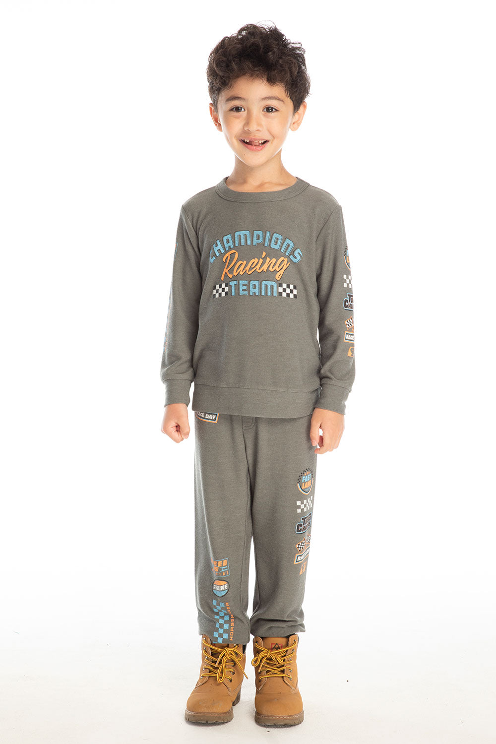 Full body view of boy wearing Chaser’s Champion Racing Team pants in safari green with matching long sleeve top on a white background