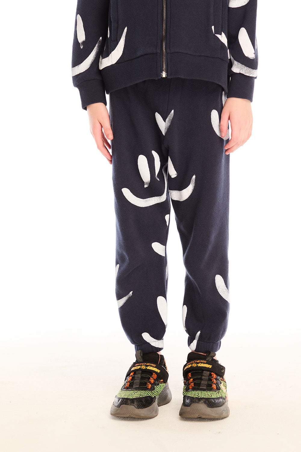 Boy wearing Chaser's navy Allover Smileys Pants with white patterns on a white background
