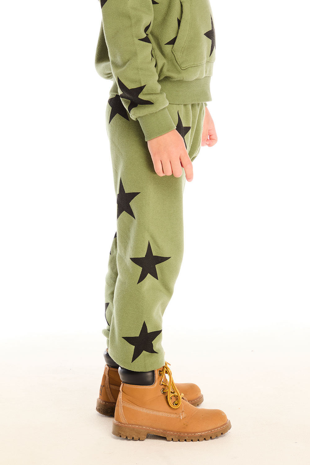 Side view of boy wearing Chaser's Allover Stars green pant with black star patterns on a white background
