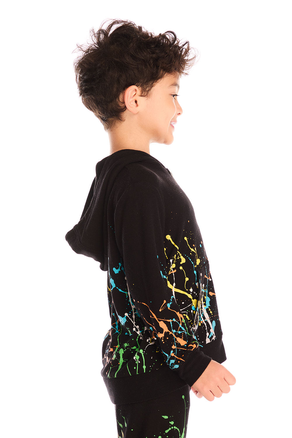 Side view of boy wearing Chaser’s Paint Splatter black hoodie with colorful splatter design and hood up on a white background