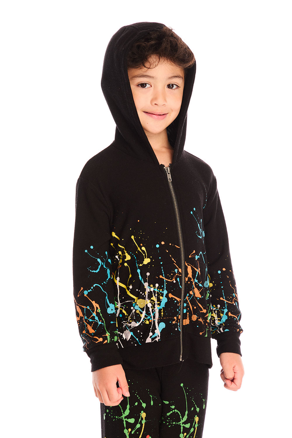  Front view of boy wearing Chaser’s Paint Splatter black zip up hoodie with colorful splatter design and hood up on a white background
