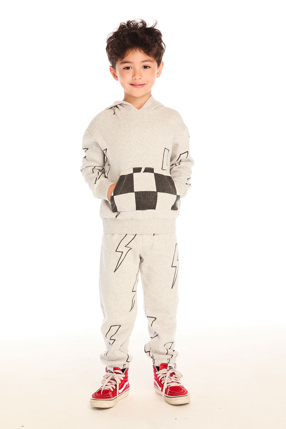 Boy wearing Chaser's gray Allover Bolts pants with lightning bolt designs and matching hoodie on a white background
