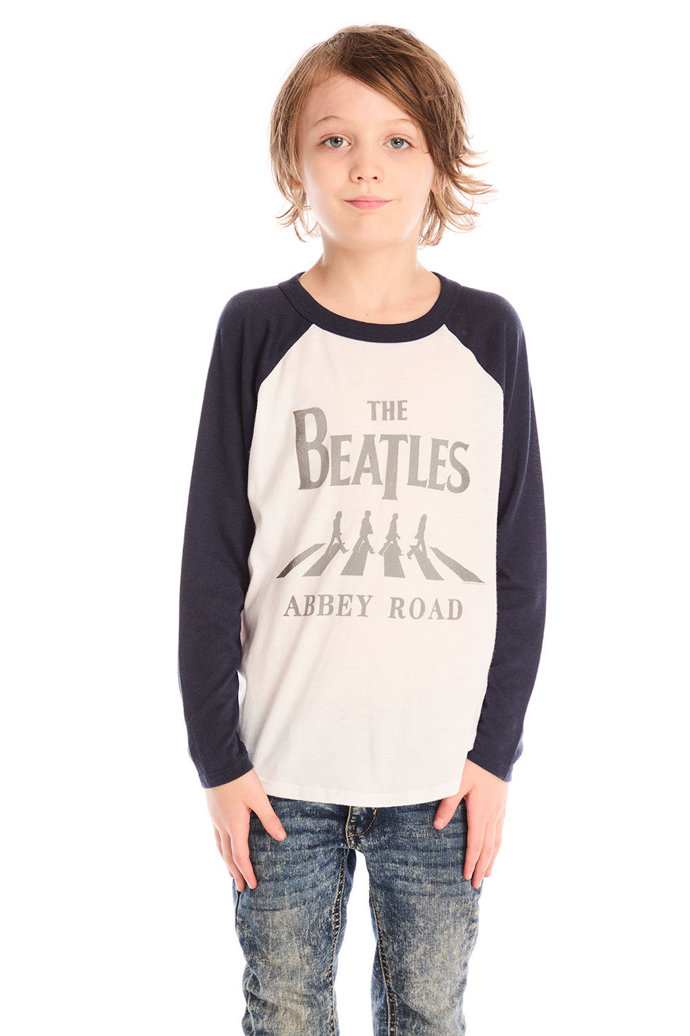 Front view of boy wearing Chaser’s The Beatles Abbey Road football tee in white with navy blue sleeves and jeans on a white background
