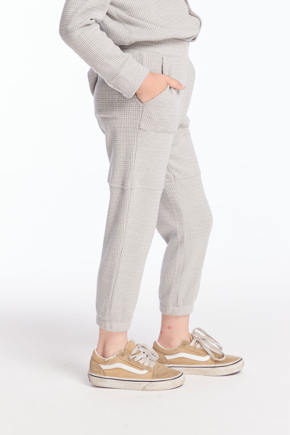 Side view of boy wearing Chaser’s heather grey Knee Seam Joggers with waffle texture against a white background