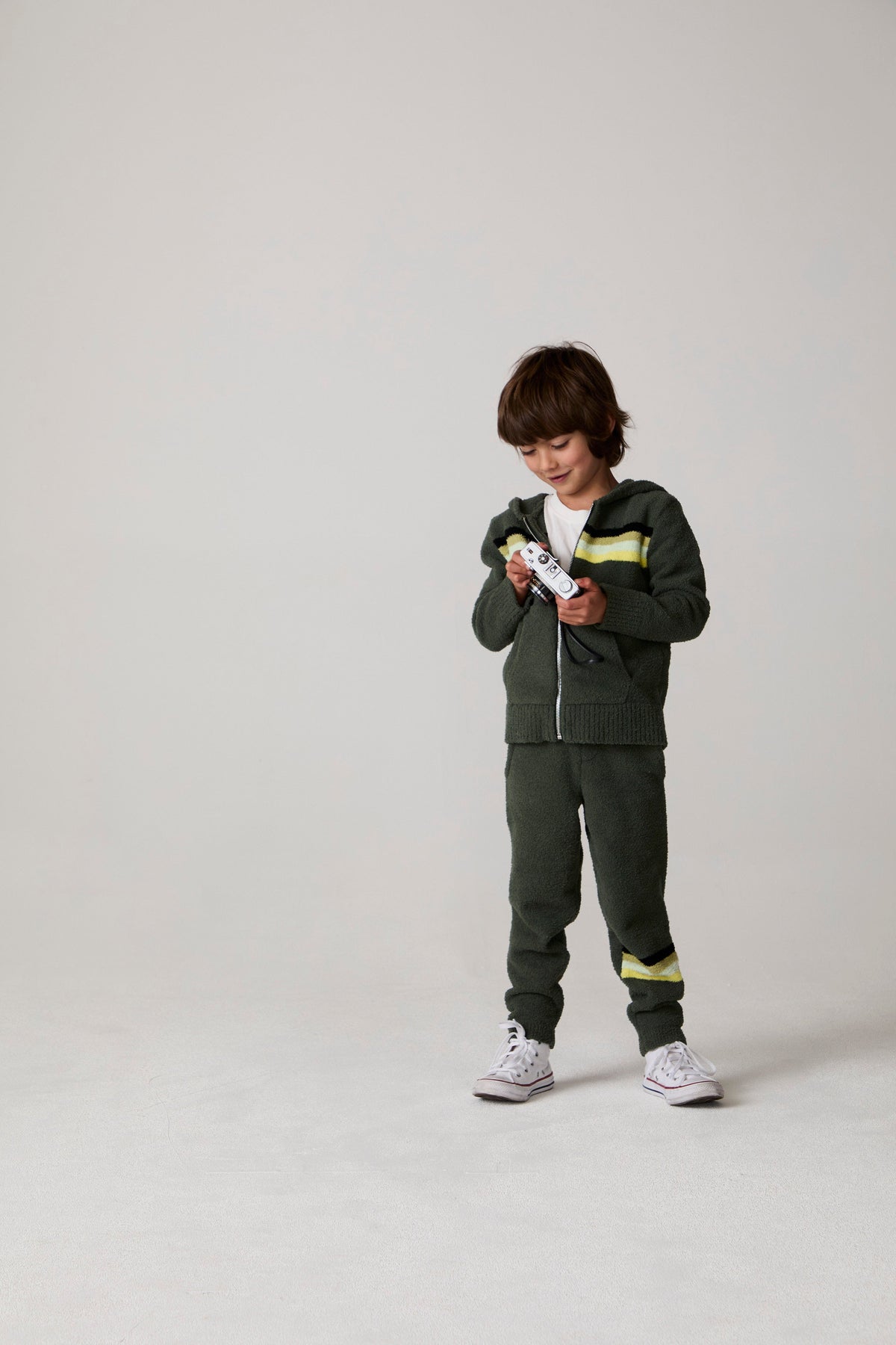 Model wearing Chaser's Lime Stripe Boys Zip-Up Hoodie in leafy green with striped detailing, editorial view