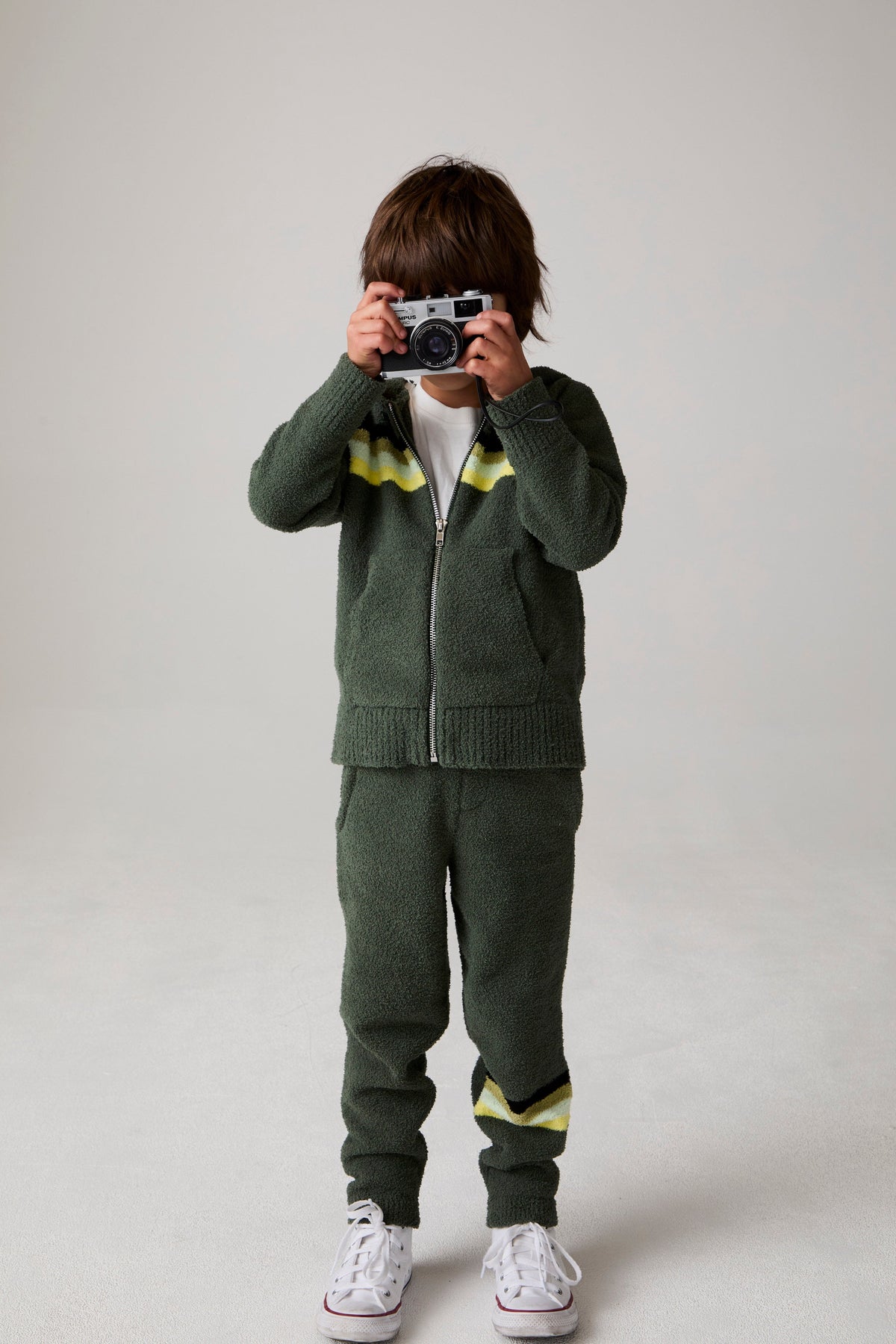 Model wearing Chaser's Lime Stripe Boys Zip-Up Hoodie in leafy green with striped detailing, editorial view