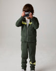 Model wearing Chaser's Lime Stripe Boys Zip-Up Hoodie in leafy green with striped detailing, editorial view