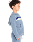 Side view of boy wearing Chaser’s Paxton Zip Up true blue hoodie and a colorful stripe on a white background