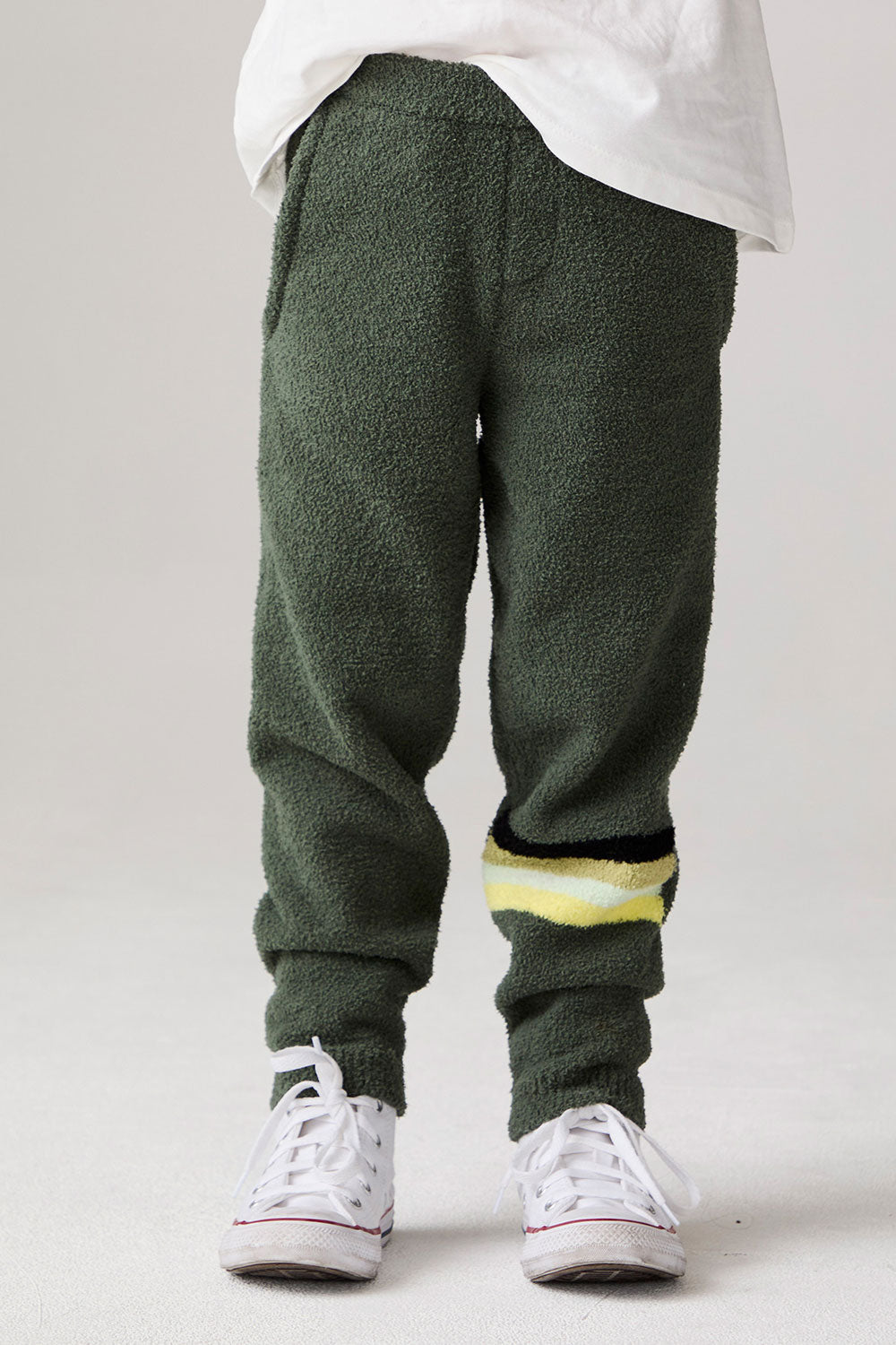 Model wearing Chaser's Lime Stripe Boys Lounge Pants in leafy green with striped detailing, front view