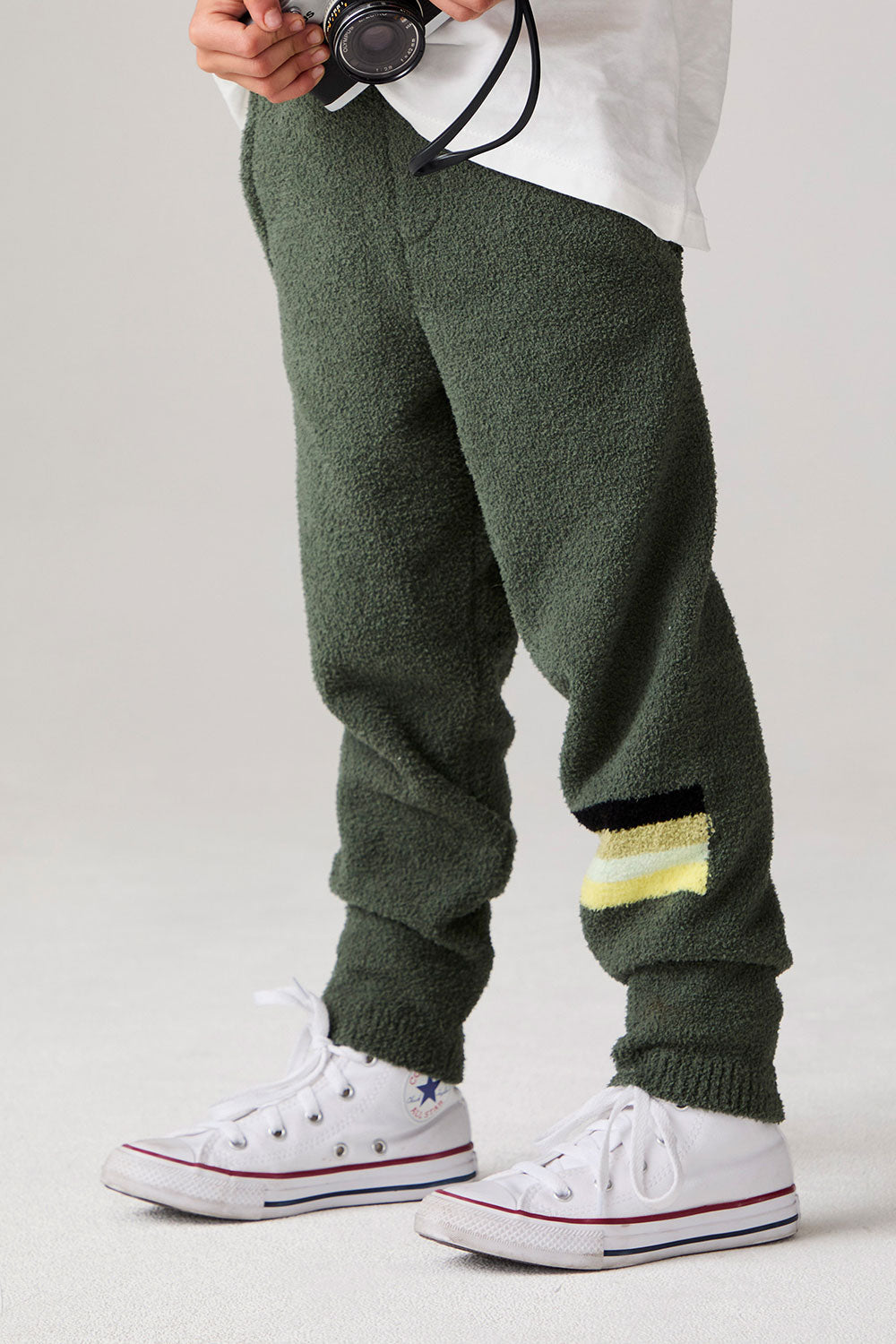 Model wearing Chaser's Lime Stripe Boys Lounge Pants in leafy green with striped detailing, side view