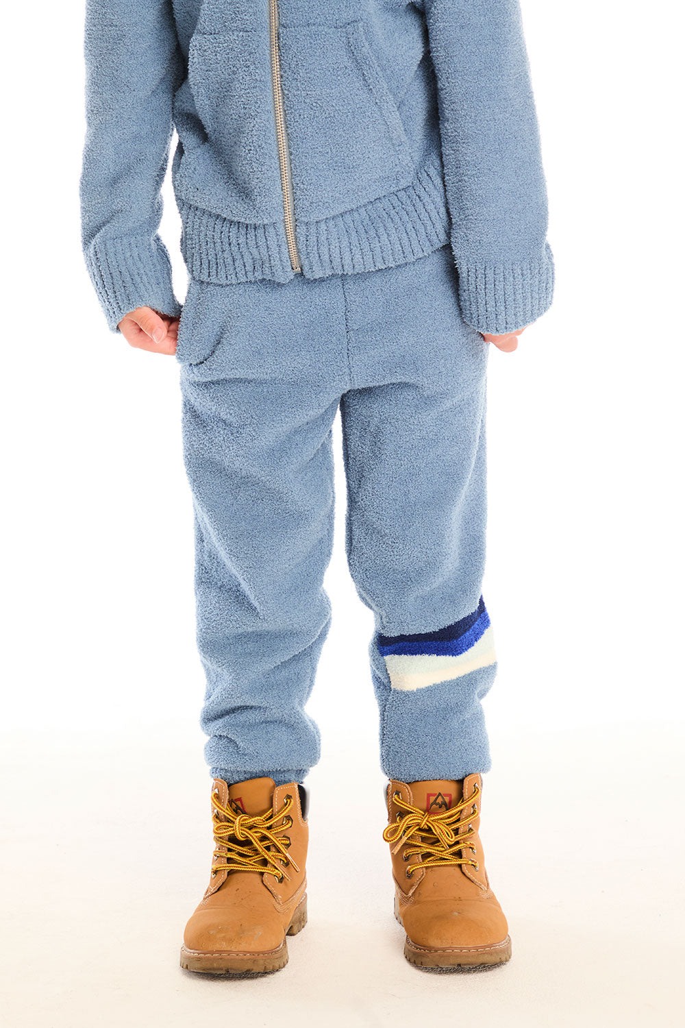 Boy wearing Chaser’s Lounge Tahoe Blue Pant with Pocket featuring dark blue and white color block on the left leg, paired with matching zip up hoodie on a white background