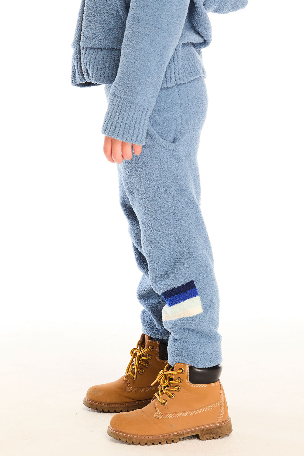 Side view of boy wearing Chaser’s Lounge Tahoe Blue Pant with Pocket with dark blue and white color block on the left leg, paired with matching zip up hoodie on a white background