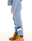 Side view of boy wearing Chaser’s Lounge Tahoe Blue Pant with Pocket with dark blue and white color block on the left leg, paired with matching zip up hoodie on a white background