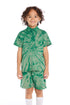 Front view of boy wearing the Chaser Kids Wild Green Tie Dye Polo Shirt featuring a button placket and spiral tie dye pattern, paired with matching Wild Green Tie Dye Cozy Beach Shorts on a white background