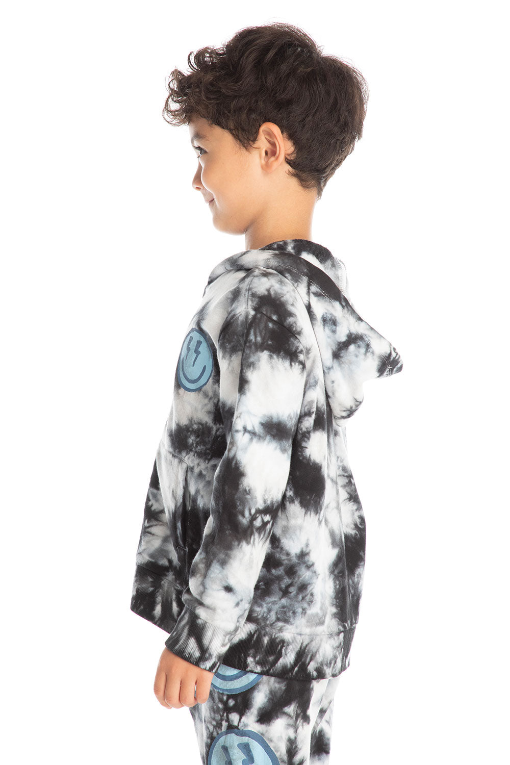Side view of boy wearing Chaser’s Smiley Bolt tie-dye zip up hoodie with smiley face lightning bolt graphic on a white background