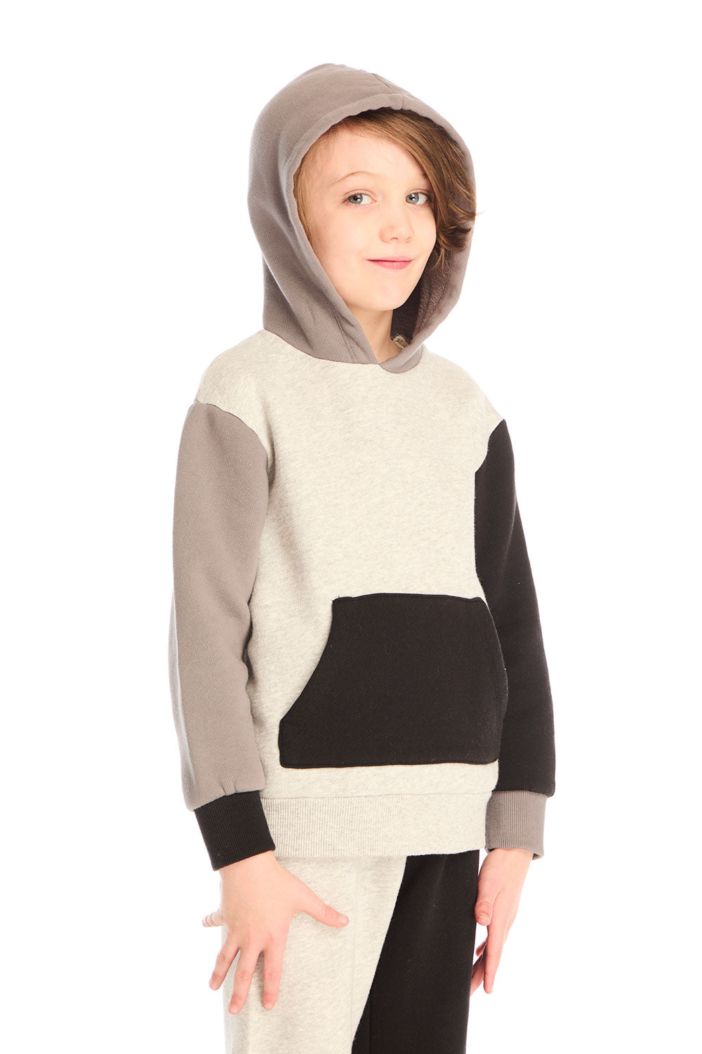Side view of boy wearing Chaser’s color-blocked long sleeve hoodie with hood up and matching pants on a white background