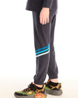Side view of boy wearing Chaser’s Avalon Lounge Pant with blue stripe strappings against a white background