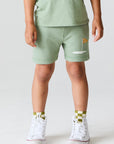 Close up view of boy wearing Chaser Kids Lets go Golfing shorts with white sneakers on a white background