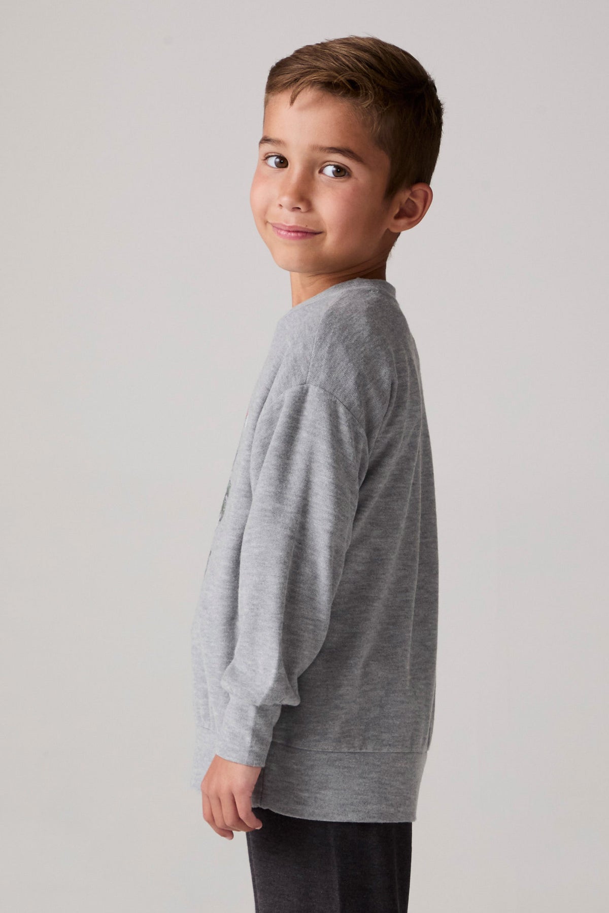 Model wearing Chaser's Santa Claws Boys Pullover in heather grey with Santa-hat dinosaur graphic, side view