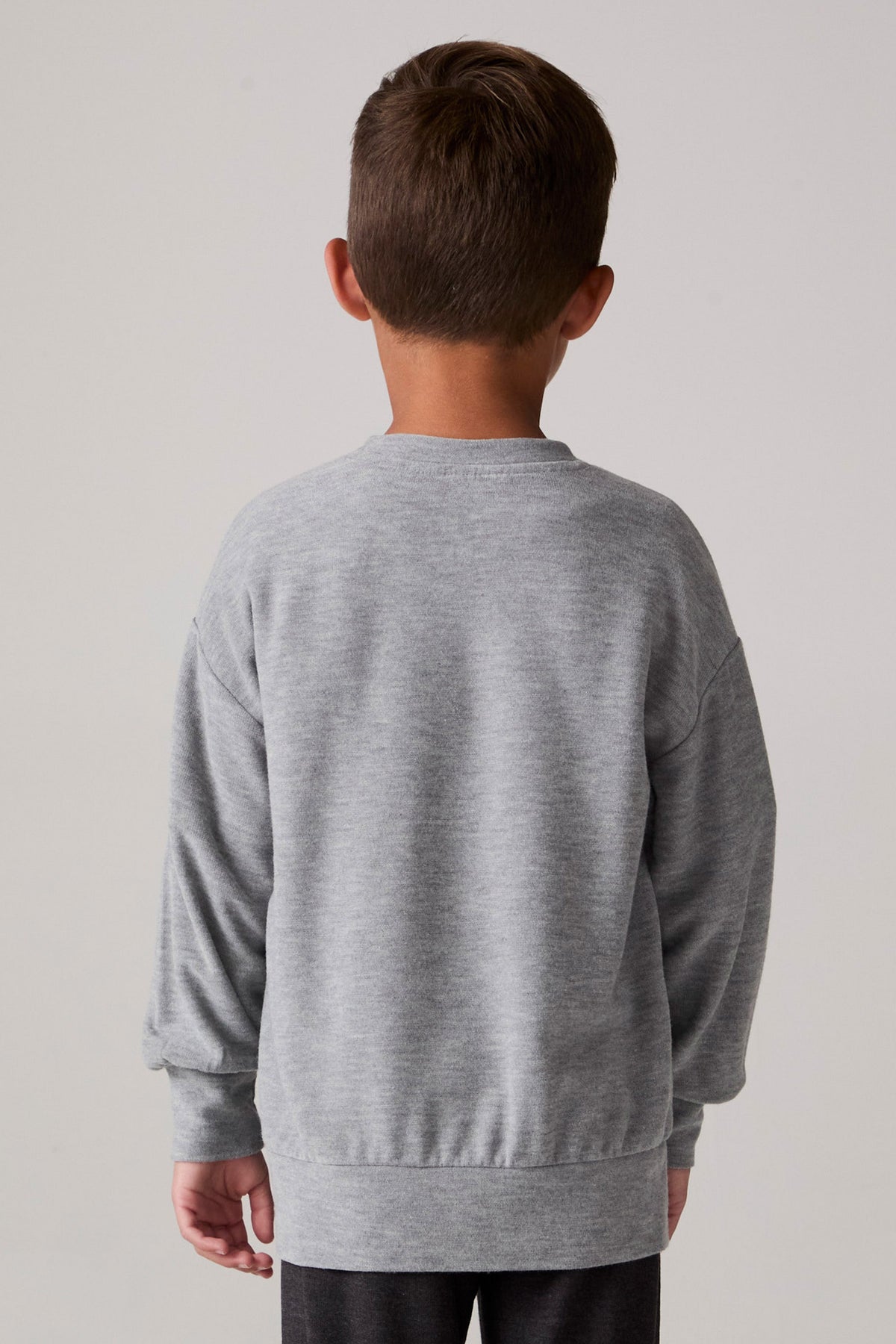 Model wearing Chaser's Santa Claws Boys Pullover in heather grey with Santa-hat dinosaur graphic, back view