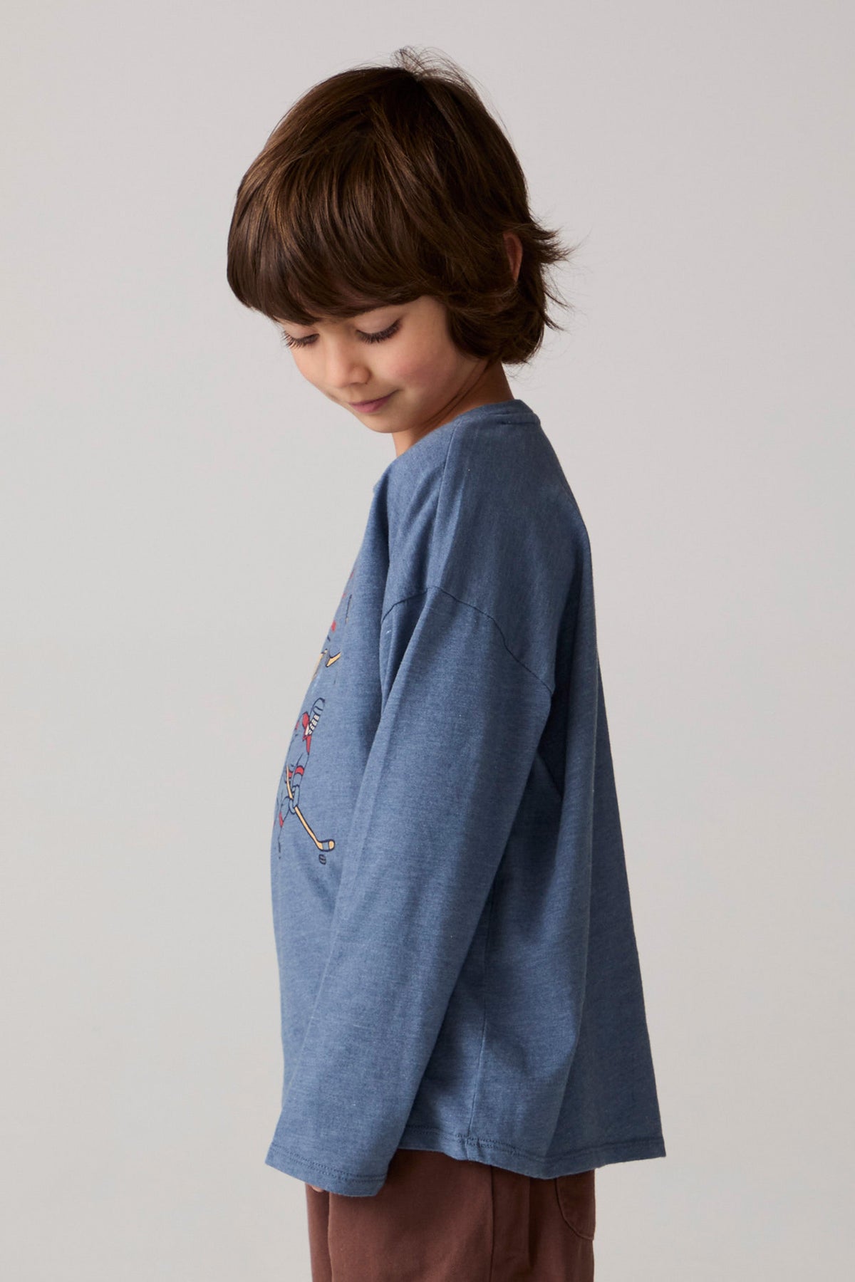 Model wearing Chaser's Champions Boys Long Sleeve Tee in blueberry jam with distinctive graphic and design details, side view