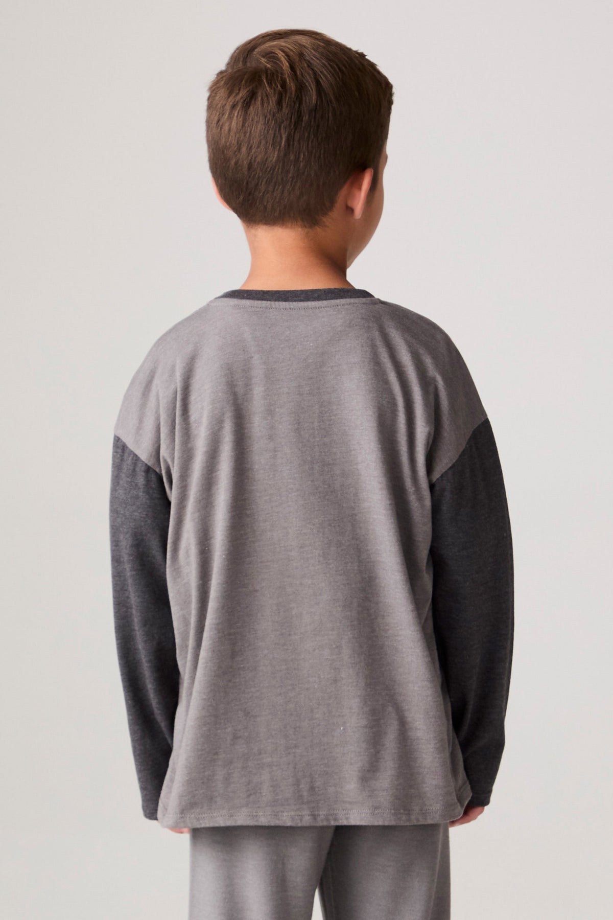Model wearing Chaser's Heroes Boys Long Sleeve Tee in charcoal with first-responder vehicle graphics, back view