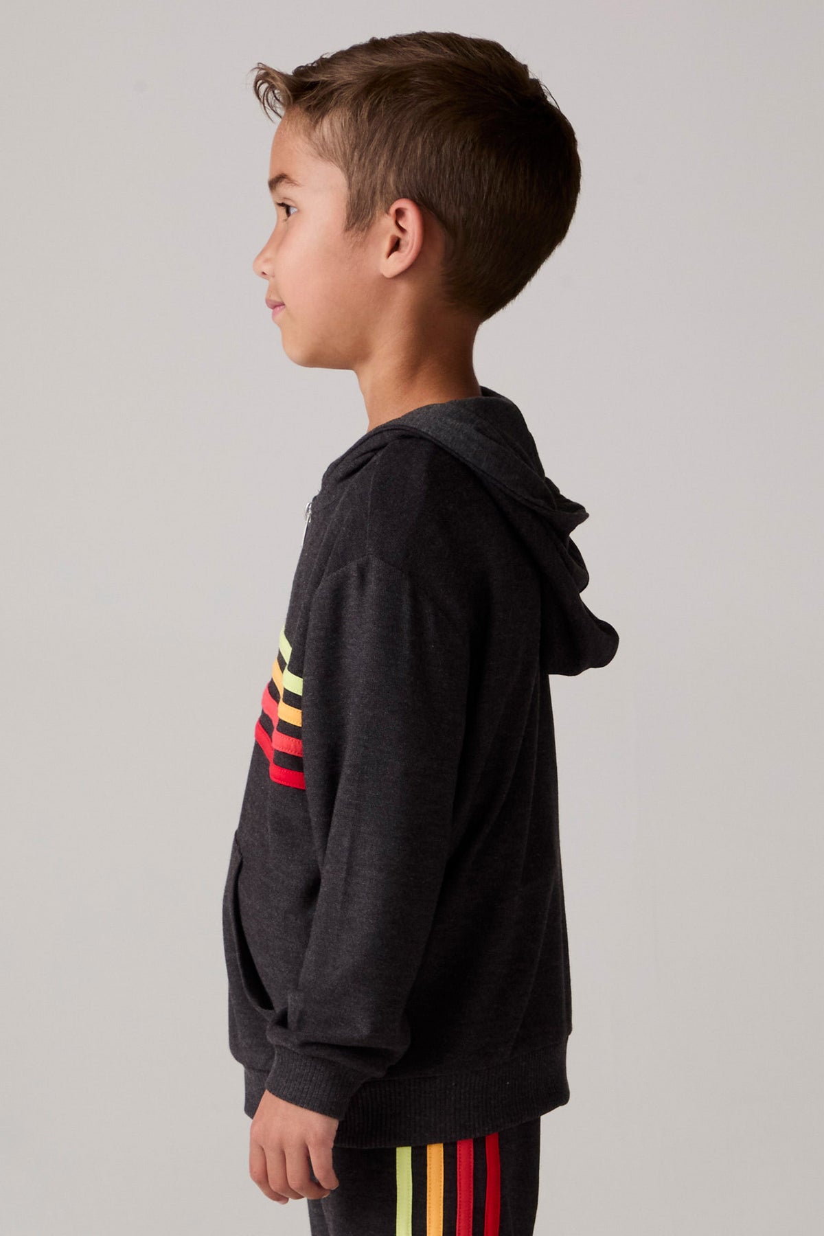 Model wearing Chaser's Vintage Black Stripe Boys Zip-Up Hoodie in Black with striped detailing, side view