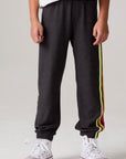 Model wearing Chaser's Vintage Black Stripe Boys Lounge Pants in Black with striped detailing, front view