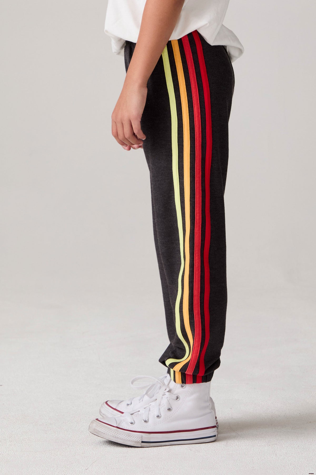 Model wearing Chaser's Vintage Black Stripe Boys Lounge Pants in Black with striped detailing, side view