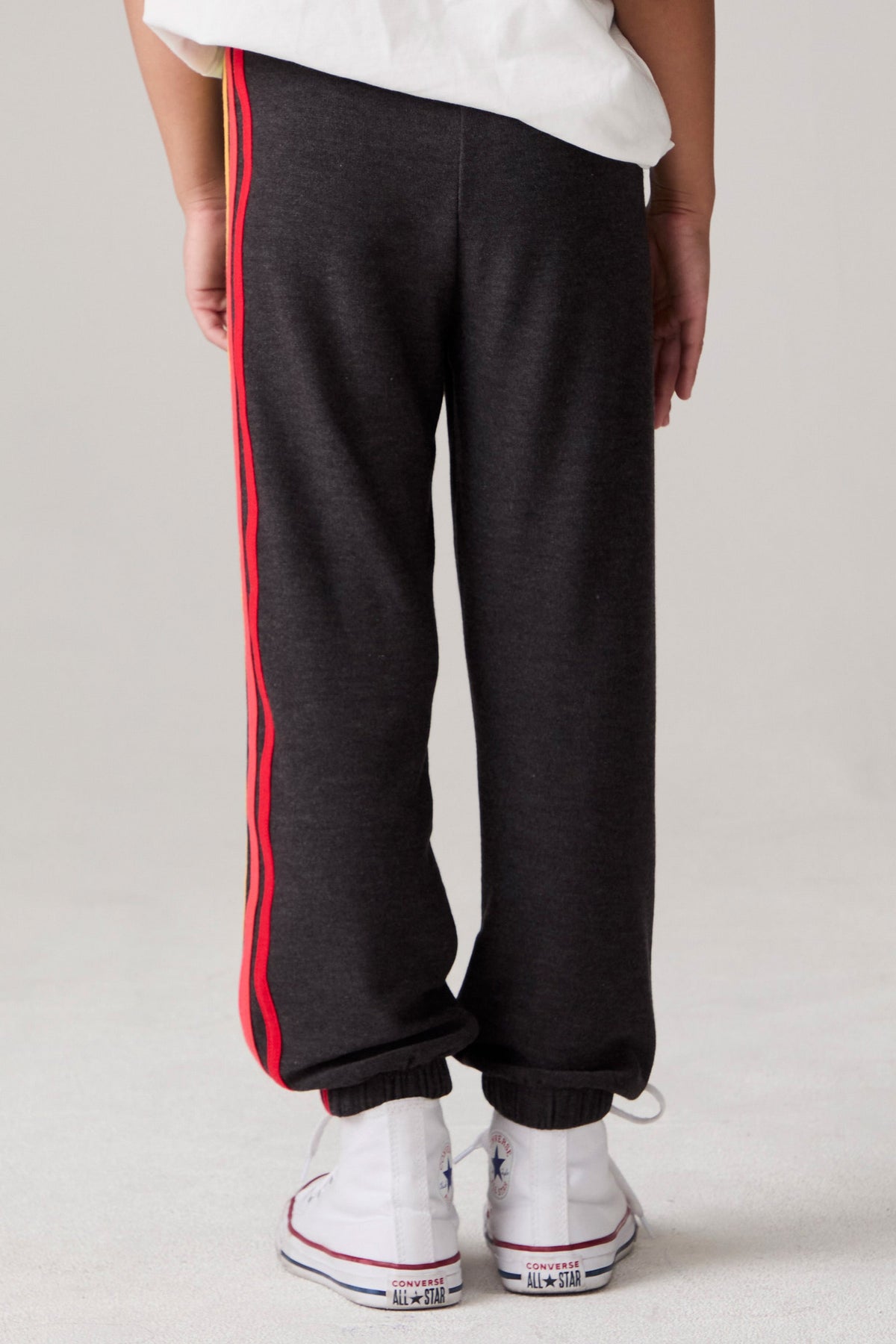 Model wearing Chaser's Vintage Black Stripe Boys Lounge Pants in Black with striped detailing, back view