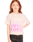 Girl wearing Chaser’s light pink Love Tee with ‘LOVE’ printed in pink and dark jeans on a white background