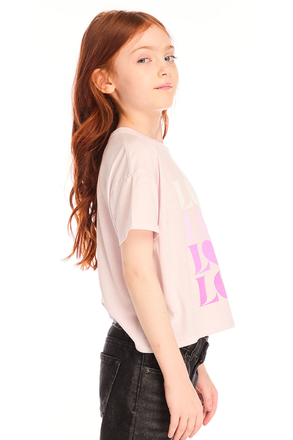 Side view of girl wearing Chaser’s light pink Love Tee with ‘LOVE’ printed in pink on a white background