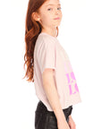 Side view of girl wearing Chaser’s light pink Love Tee with ‘LOVE’ printed in pink on a white background