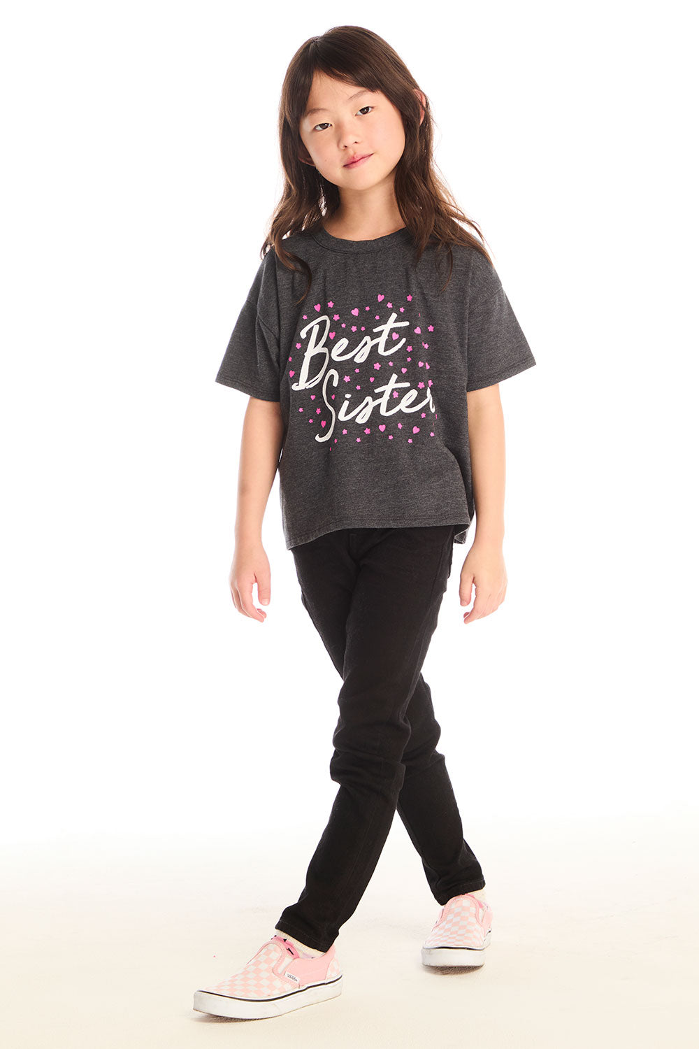 Full body view of young girl wearing Chaser’s Best Sister black tee with black jeans on a white background