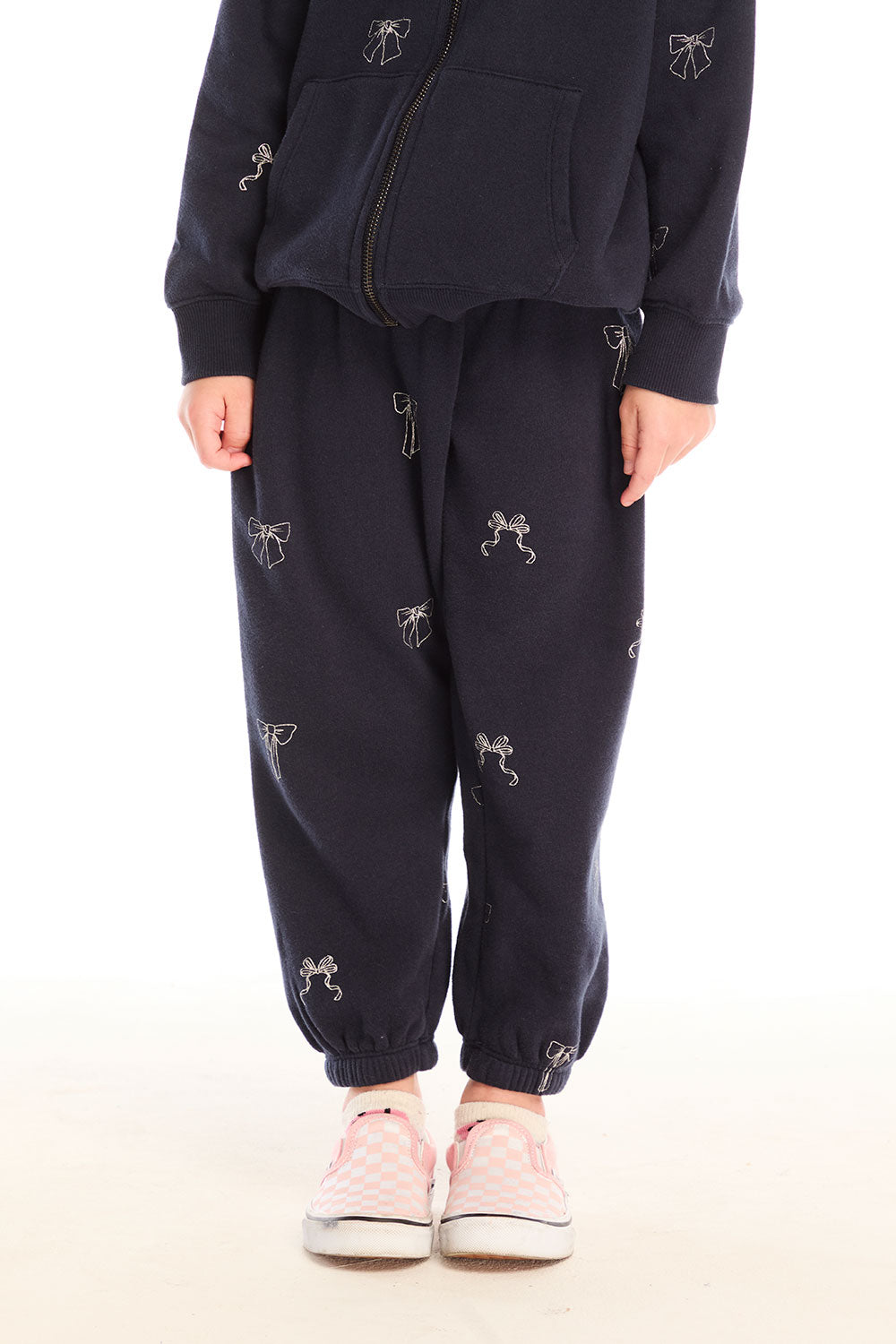 Girl wearing Chaser’s navy blue Tossed Glitter Bows Pants with embroidered bow designs on a white background